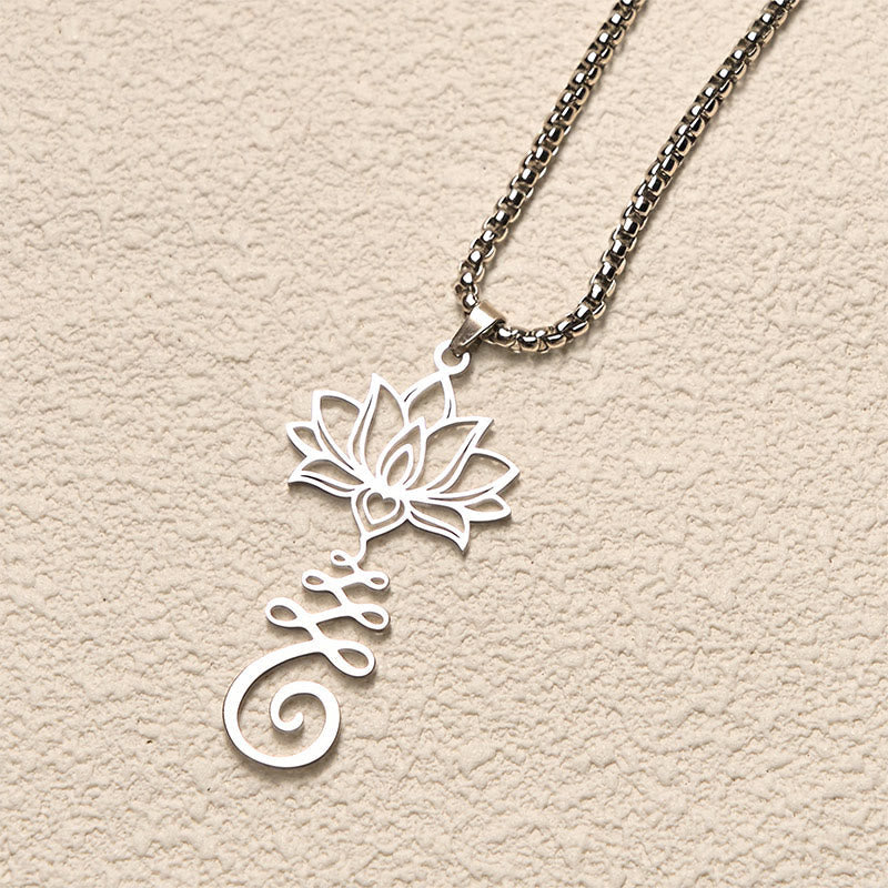Chakra Lotus Necklace – Silver lotus-Om pendant at elevated angle on cream surface, spiritual jewelry