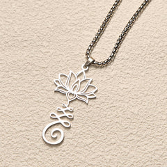 Chakra Lotus Necklace – Silver lotus-Om pendant at elevated angle on cream surface, spiritual jewelry