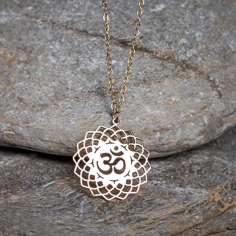 Gold Om necklace with lotus cutout mandala, on stone backdrop