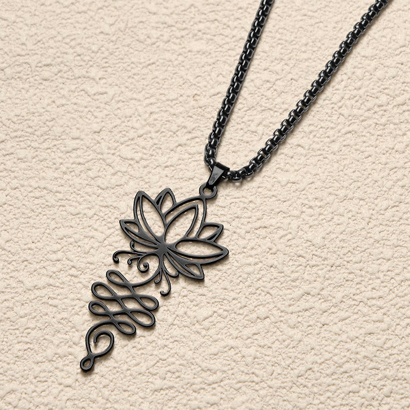 Lotus Vines Chakra Necklace – Black lotus-unalome pendant flat lay on cream surface, enlightenment pendant