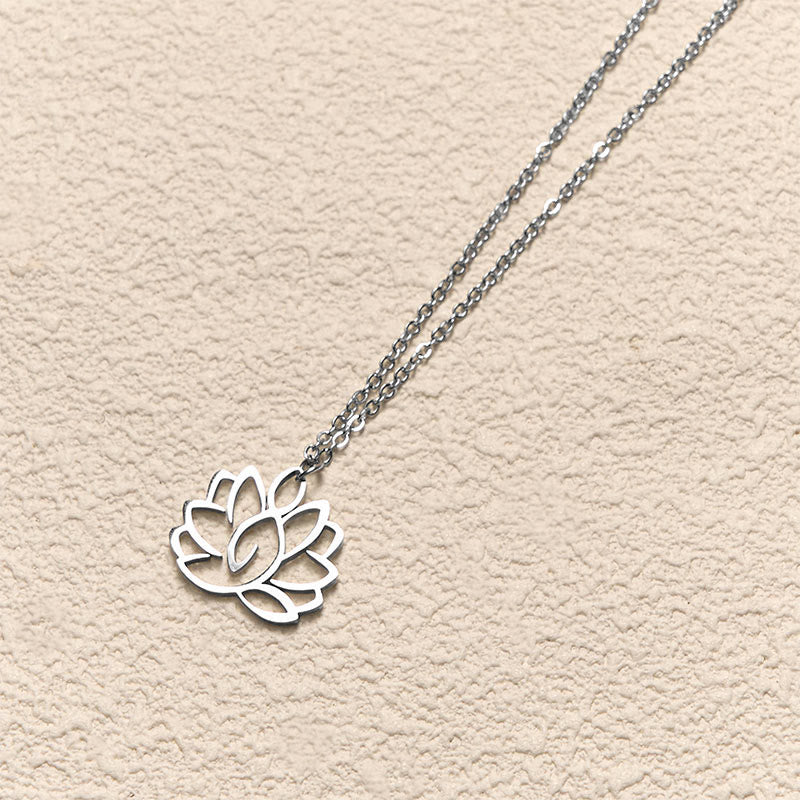 Hollow Lotus Necklace – Silver openwork lotus pendant on textured cream at angled view, enlightenment symbol