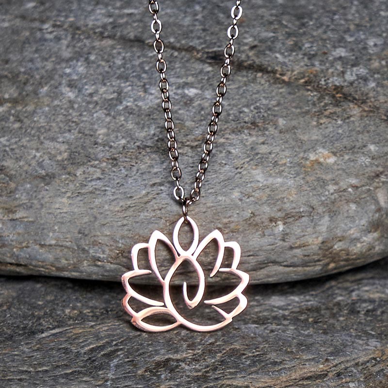 Hollow Lotus Necklace – Rose gold lotus pendant with dark chain on stone, purity enlightenment jewelry