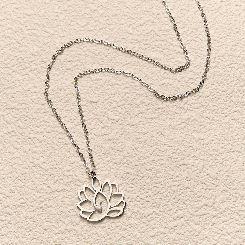 Hollow Lotus Necklace – Silver cutout lotus pendant flat-laid on cream textured background, purity pendant