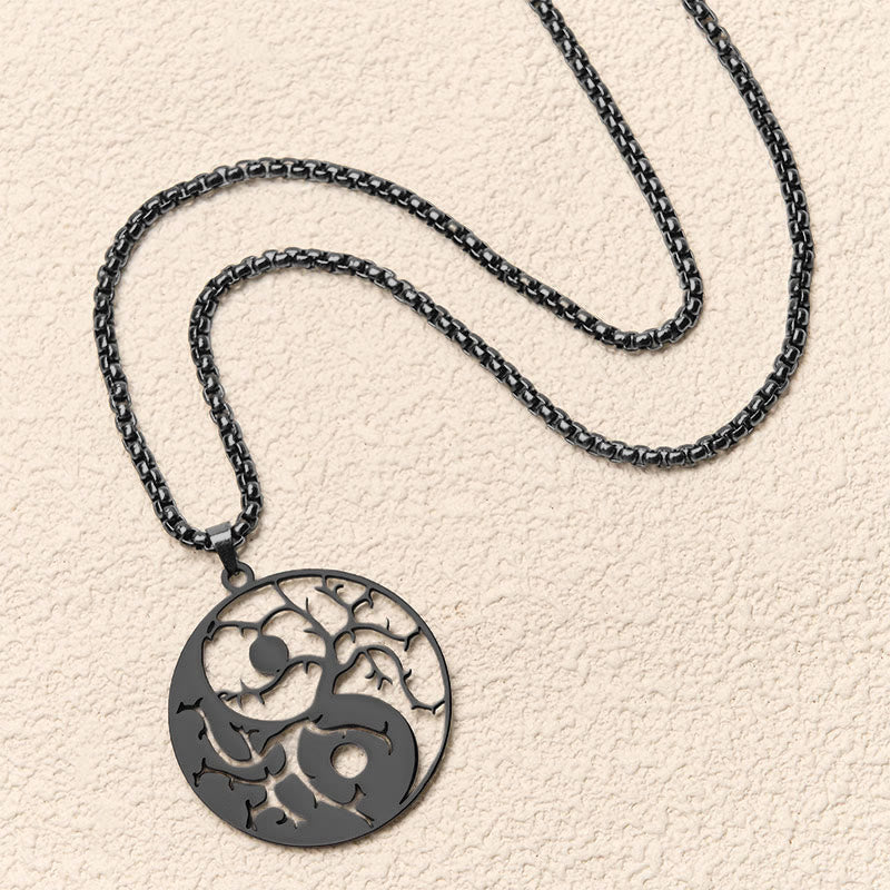 Yin Yang Branches Necklace – Black pendant flat lay on cream surface, tree of life jewelry