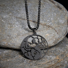 Yin Yang Branches Necklace – Black pendant on gray stone surface, stainless steel pendant