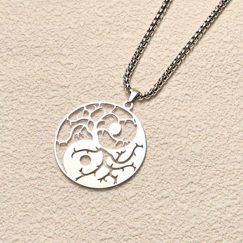 Yin Yang Branches Necklace – Silver pendant flat lay on cream texture, stainless steel