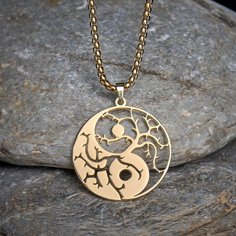 Yin Yang Branches Necklace – Gold pendant on gray stone surface, balance pendant