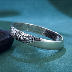 Heart Sutra Koi Fish Copper Bracelet – low-angle close-up of koi scales and bubble motifs, hammered interior on teal