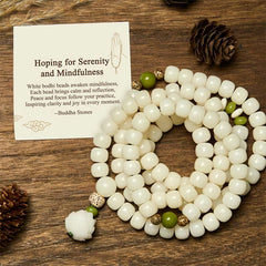 Bodhi Seed Lotus Mala - coiled white prayer beads with green jade accents on wooden table, serene