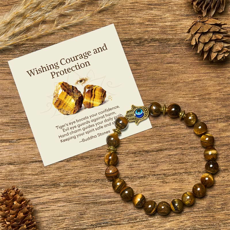 Tiger eye gemstone bracelet with Hamsa evil eye charm and Buddha Stones card on rustic wood