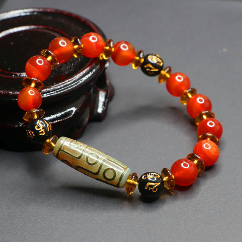 Red Agate Nine-Eye Dzi Bead Bracelet – directional lighting on eye-pattern beads and gold-inscribed mantra beads, wood stand