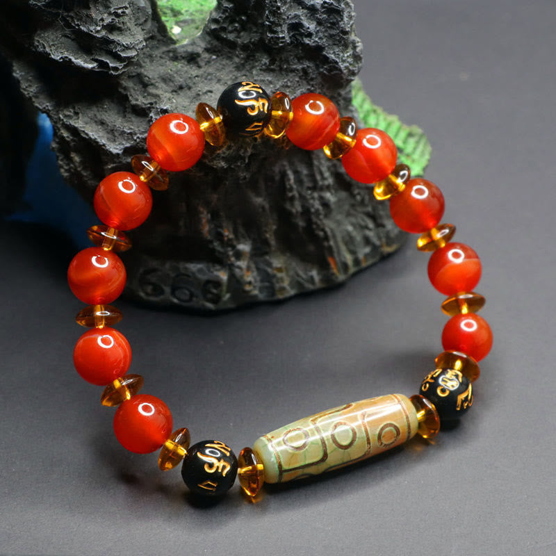 Red Agate Nine-Eye Dzi Bead Bracelet – dramatic lighting on carved stone prop, translucent carnelian and central dzi bead