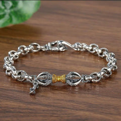 Copper Vajra Om Mani Padme Hum Bracelet – silver vajra centerpiece with gold accent on wooden surface, spiritual jewelry
