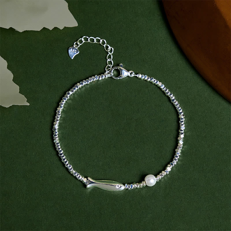 Silver Koi Fish Pearl Luck Bracelet – top-down flat-lay, koi charm and pearl on beaded chain, dark green bg