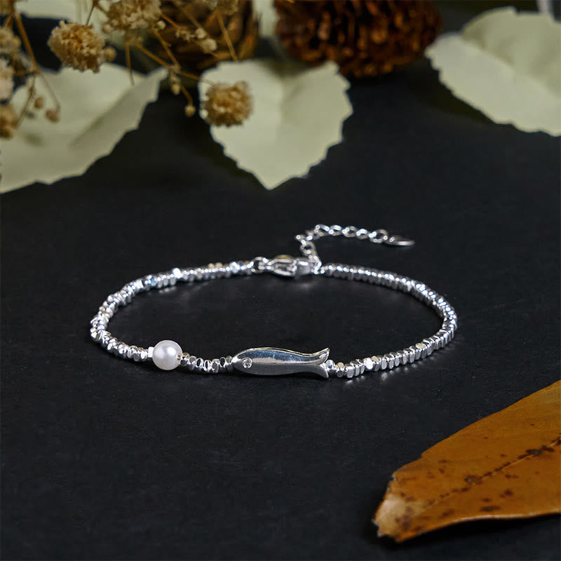 Silver Koi Fish Pearl Luck Bracelet – three-quarter angle on black with dried botanicals and pine cone props