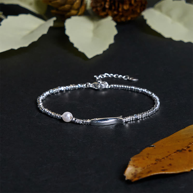 Silver Koi Fish Pearl Luck Bracelet – angled view on black surface, koi charm with pearl and dried flowers