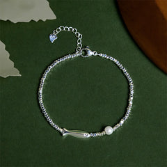 Silver Koi Fish Pearl Luck Bracelet – top-down flat-lay, koi charm and pearl on beaded chain, dark green bg
