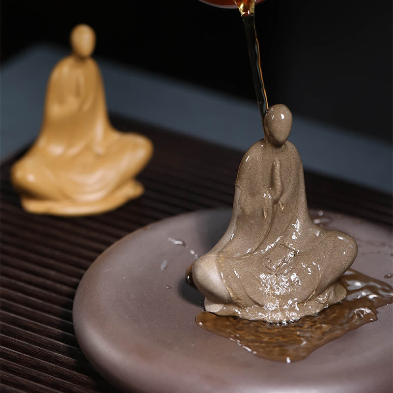 Ceramic Formless Buddha Prayer Statue – tea poured over gray statue, water glistening on ceramic, ceremonial cleansing moment