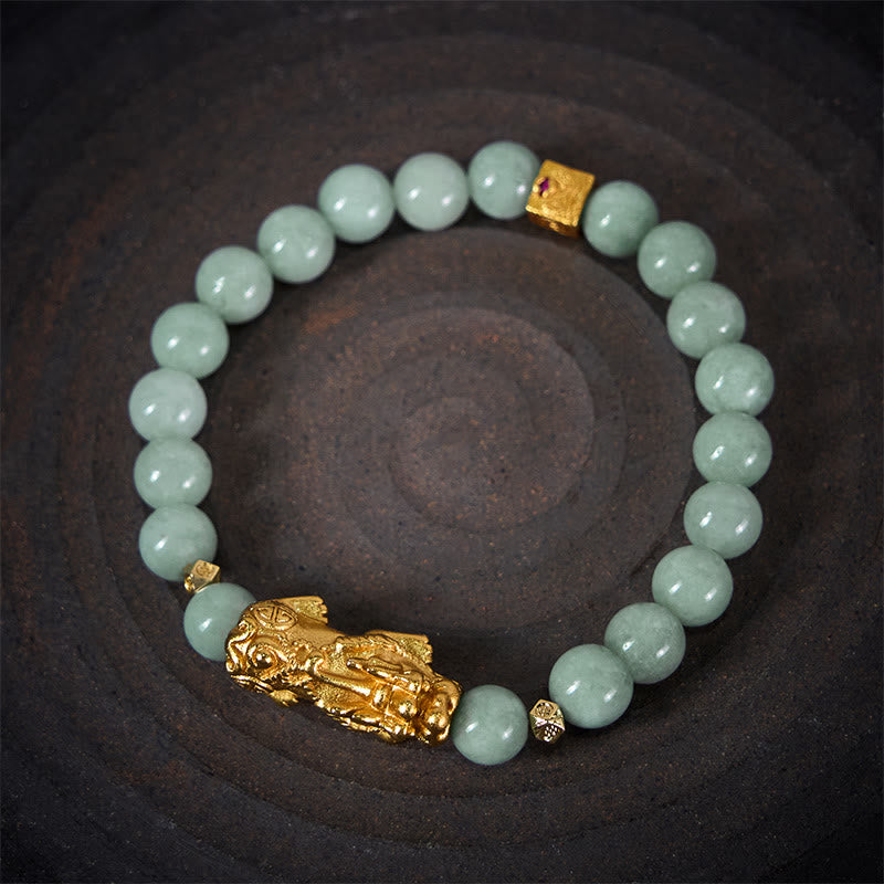 Golden Pi Xiu Charm Jade Prosperity Beaded Bracelet – Top view of green jade bracelet with gold Pi Xiu on dark ceramic plate