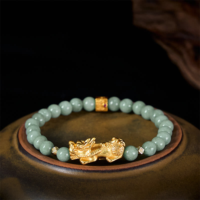 Golden Pi Xiu Charm Jade Prosperity Beaded Bracelet – Green jade bracelet with gold Pi Xiu on dark ceramic plate, side angle