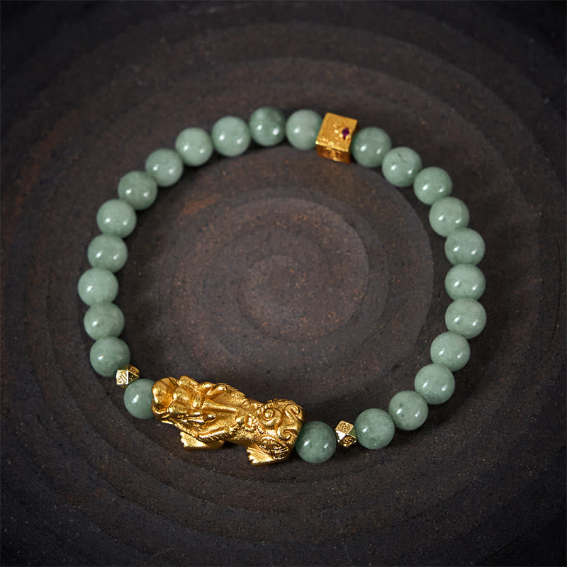 Golden Pi Xiu Charm Jade Prosperity Beaded Bracelet – Overhead view of green jade bracelet with gold Pi Xiu on dark plate