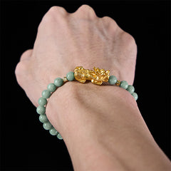 Golden Pi Xiu Charm Jade Prosperity Beaded Bracelet – Hand holding phone wearing jade Pi Xiu bracelet, lifestyle shot