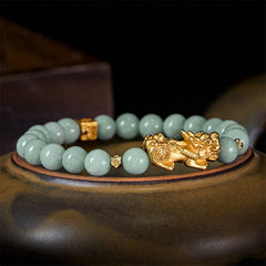Golden Pi Xiu Charm Jade Prosperity Beaded Bracelet – Green jade bracelet with gold Pi Xiu on brown ceramic, side angle