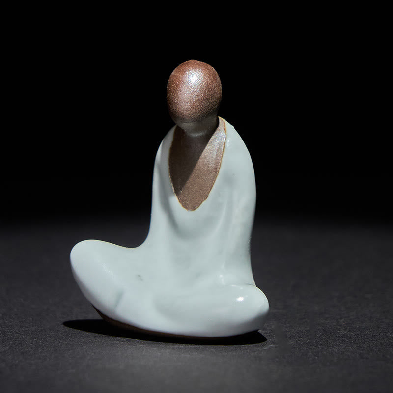 Ceramic Formless Buddha Meditating Statue – front view, white celadon glaze with brown head, dark studio backdrop, zen decor