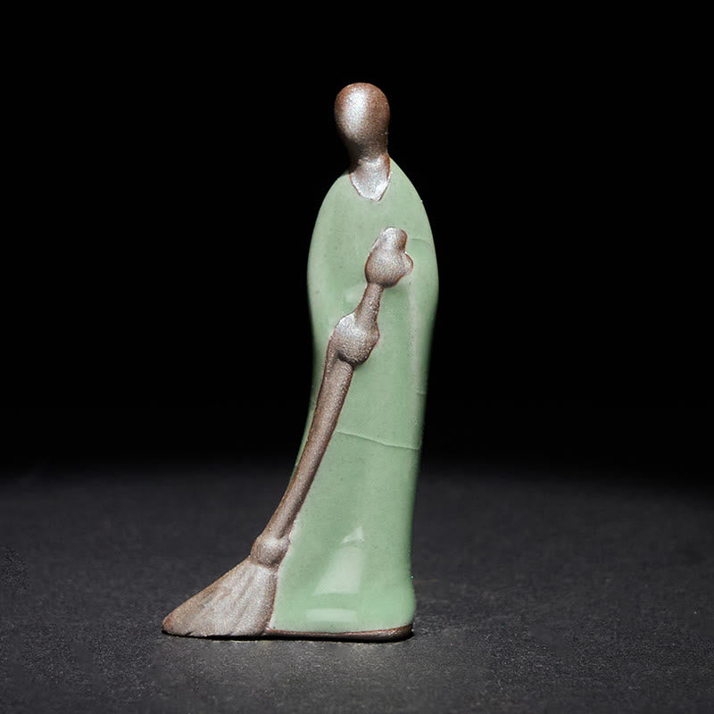Ceramic Sweeping Monk Buddha Statue – celadon monk with broom three-quarter front, dark studio