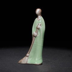 Ceramic Sweeping Monk Buddha Statue – celadon sweeping monk straight front view, dark studio zen