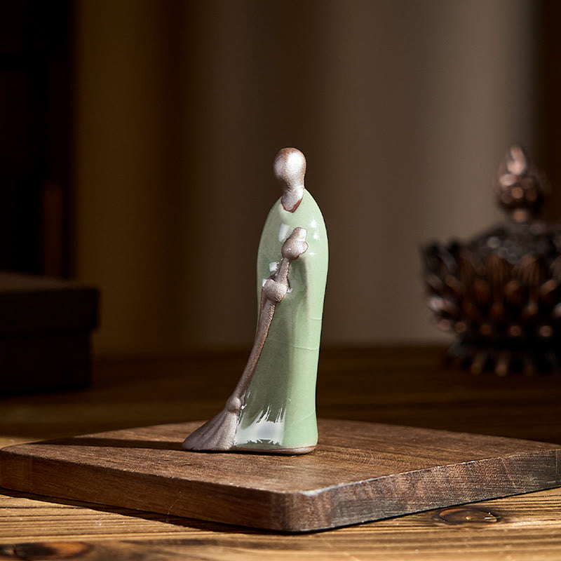 Ceramic Sweeping Monk Buddha Statue – monk on wood base with incense burner, natural light