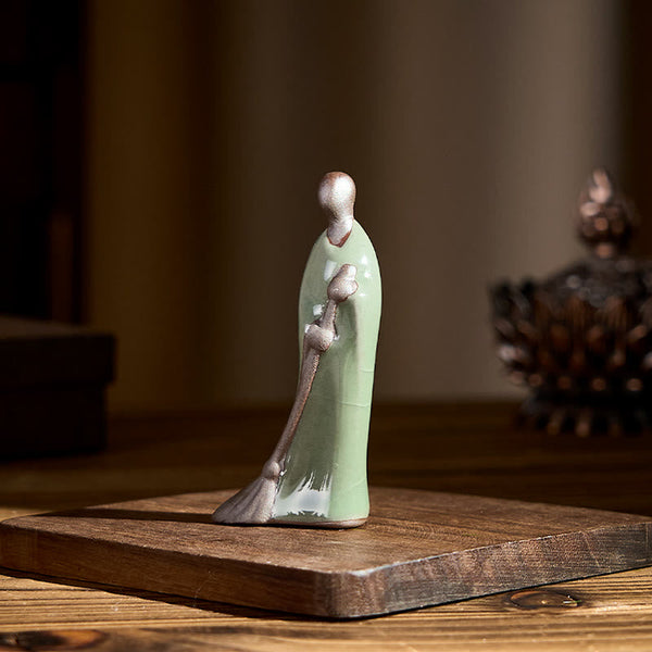 Ceramic Sweeping Monk Buddha Statue – monk on wood base with incense burner, natural light
