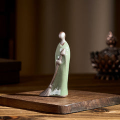 Ceramic Sweeping Monk Buddha Statue – monk on wood base with incense burner, natural light