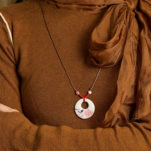 Ceramic Peony & Lotus Pendant – Bird and blossom pendant worn with brown knit on-model, floral necklace
