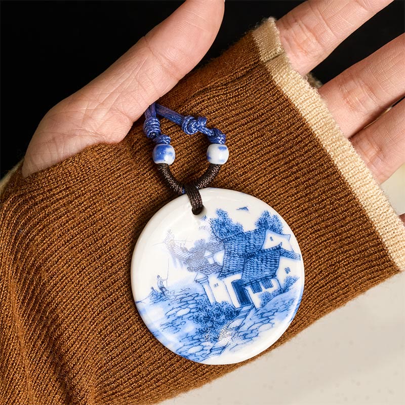 Ceramic Peony & Lotus Pendant – Landscape with pagoda held on brown knit sleeve, blue-white pendant