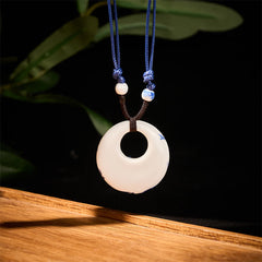 Ceramic Peony & Lotus Pendant – White disc with blue floral edge in dark studio, ceramic jewelry