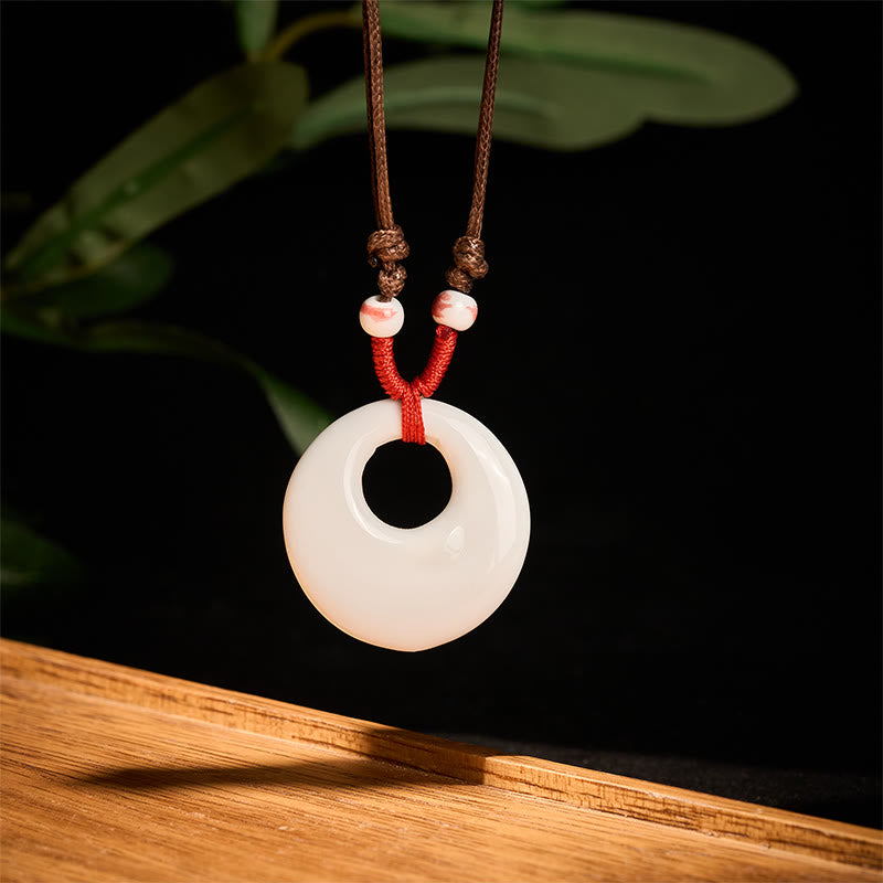 Ceramic Peony & Lotus Pendant – White bi disc with red cord and pink beads on wood, ceramic necklace