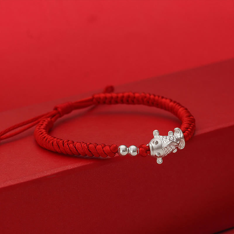 999 Silver Koi Fish Red String Bracelet – red cord bracelet with silver koi fish charm on red geometric display platform