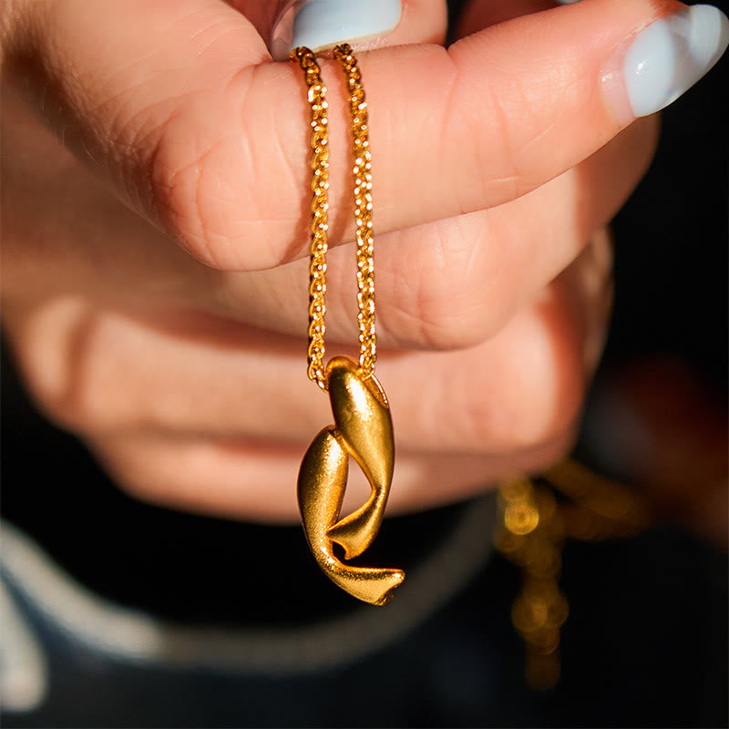 Double Koi Fish Gold Necklace Pendant – pendant held in hand against black bg, 24K gold double koi jewelry
