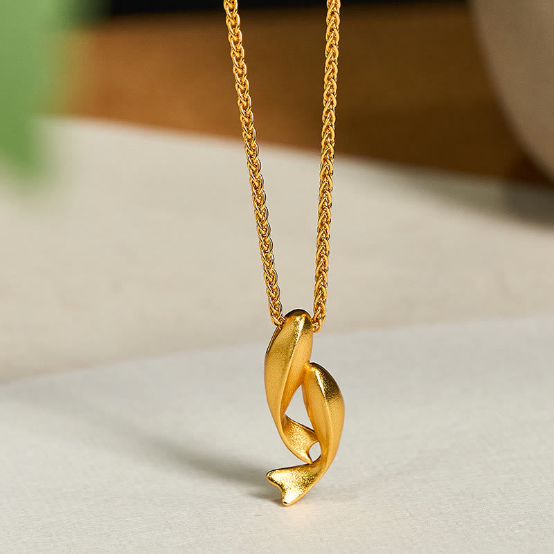 Double Koi Fish Gold Necklace Pendant – intertwined koi on marble surface three-quarter, 24K gold plated brass