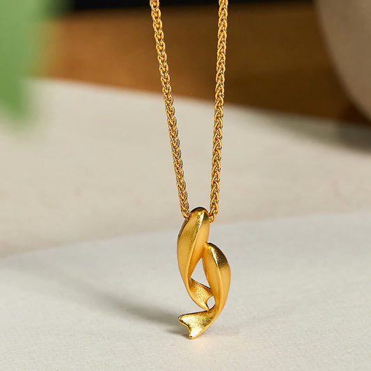 Double Koi Fish Gold Necklace Pendant – intertwined koi on marble surface three-quarter, 24K gold plated brass