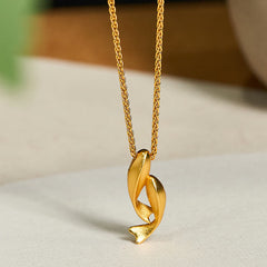 Double Koi Fish Gold Necklace Pendant – intertwined koi on marble surface three-quarter, 24K gold plated brass