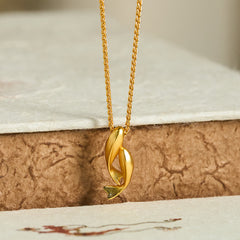 Double Koi Fish Gold Necklace Pendant – gold pendant on crackled brown texture low angle, wealth jewelry