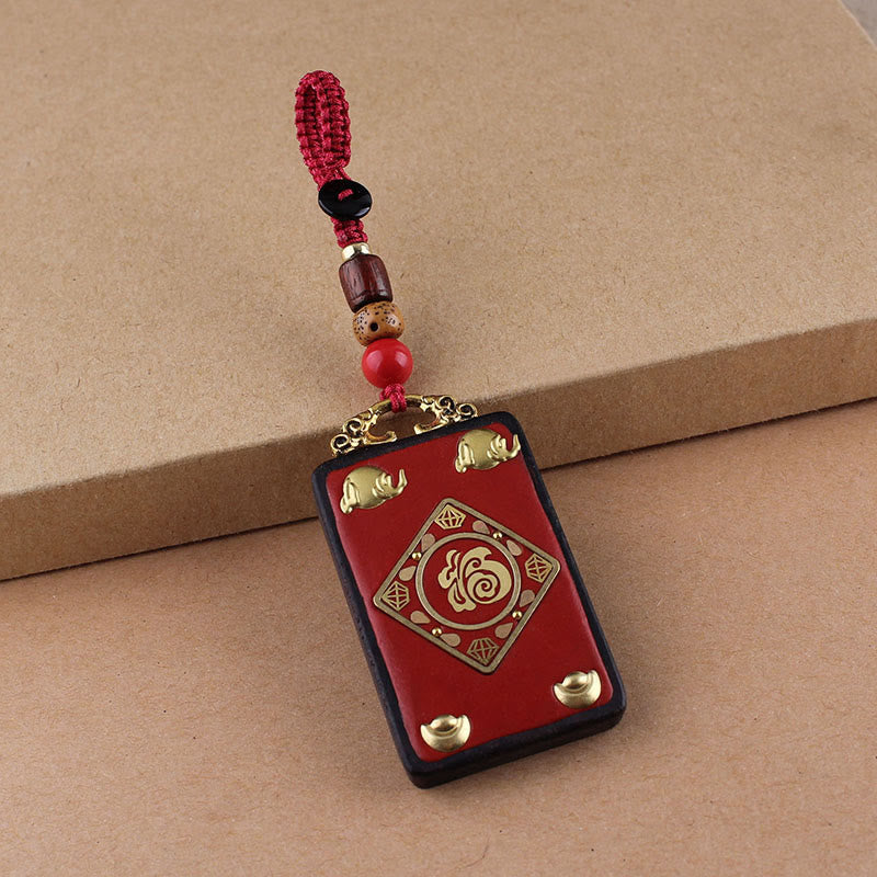 Ebony Koi Fish Fu Character Keychain – red cinnabar Fu pendant with gold elephant motifs and beaded red cord on kraft paper