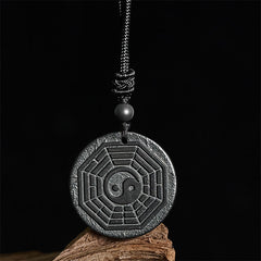 Shungite Stone Yin Yang Bagua Necklace - front on dark wood, feng shui jewelry