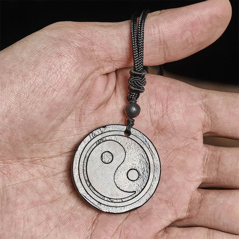 Natural Shungite Carved Yin Yang Pendant - held in hand for scale, shungite pendant