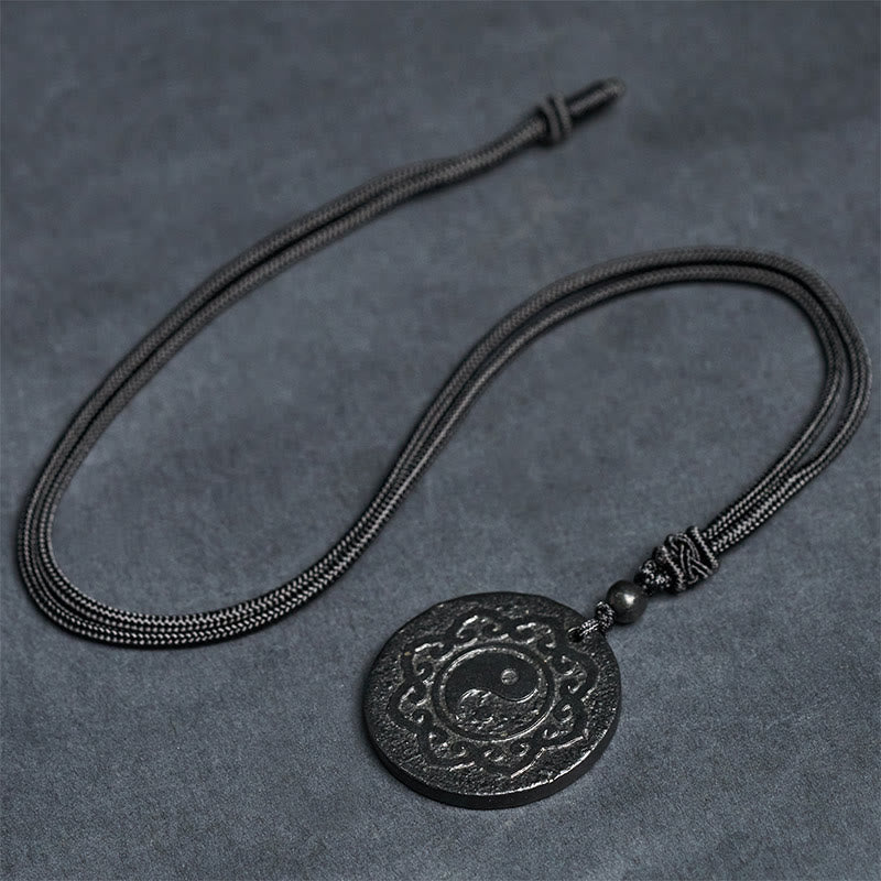 Shungite Yin Yang Pendant – flat lay on gray surface, adjustable cord necklace