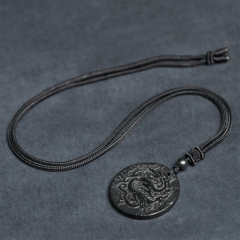 Shungite Dragon Necklace - dragon carving on gray stone surface, knotted cord detail, Focus