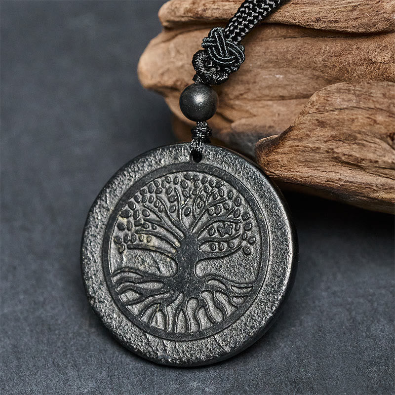 Tree of Life Shungite Stone Necklace – pendant leaning on natural wood showing textured surface, shungite pendant