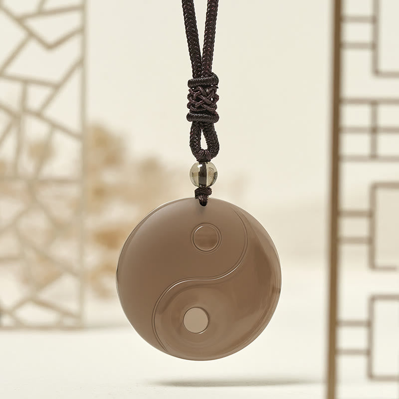 Ice Obsidian Yin Yang Pendant – lifestyle shot with East Asian lattice backdrop, crystal necklace